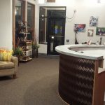An office lobby with two chairs, plants & a semi-circle counter.